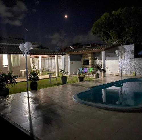 a swimming pool in the middle of a yard at night at Casa parque do Jacuípe in Camaçari