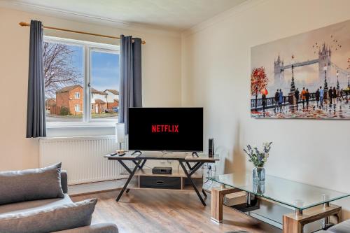 a living room with a tv and a glass table at Immaculate Two Bedroom House with Parking in Bedford