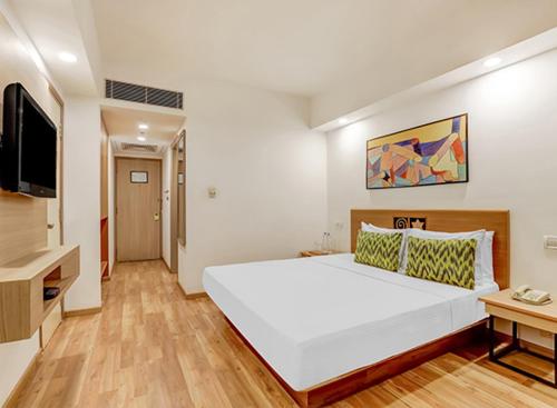 een slaapkamer met een groot wit bed en een televisie bij H R G DESTINY in Indore