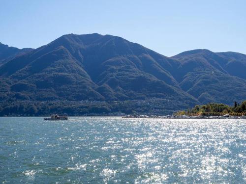 um barco na água com montanhas ao fundo em Appartamento fronte lago em Muralto