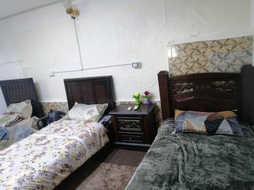 a bedroom with two beds and a night stand with a bedskirts at Red rose apartment in Jerash