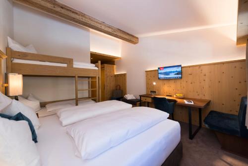 a hotel room with two beds and a desk at BichlAlm Berggasthof in Kitzbühel