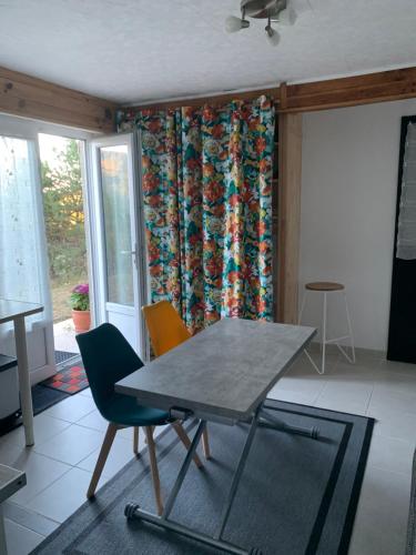 - une table et des chaises dans une pièce avec rideau dans l'établissement T2 au calme montagne et lac, à La Bâtie-Vieille