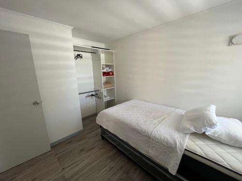 - une chambre blanche avec un lit et un placard dans l'établissement Casa en Villa Galilea, à Curicó
