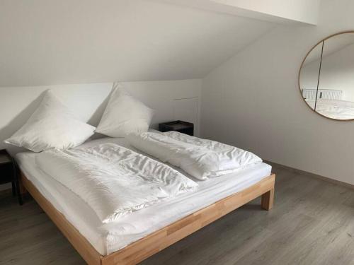 a bed with white sheets and a mirror in a room at Ferienapartment Allgäu-Idyll (Dietmannsried) in Dietmannsried