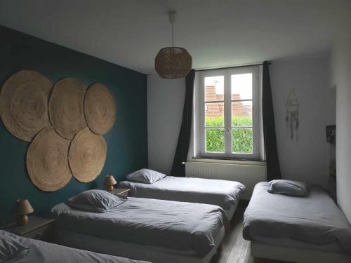 une chambre avec trois lits et une fenêtre dans l'établissement Le Presbytère de la côte d'opale, à Nempont-Saint-Firmin