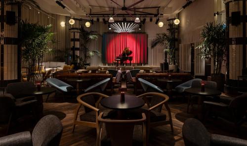 a man sitting on a stage in front of a red curtain at The George Tel Aviv in Tel Aviv