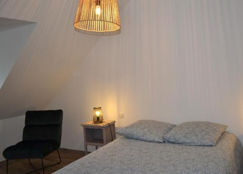 una camera con letto, sedia e lampada di Gîte de charme à la ferme - 8 personnes a Landrévarzec
