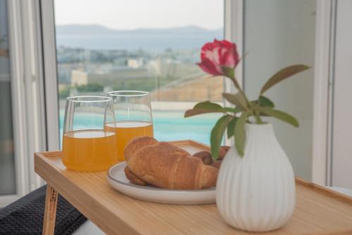 a table with a plate of bread and two glasses of orange juice at Nèsoi Villas Naxos in Naxos Chora