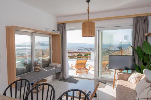 a living room with a couch and chairs and a balcony at Nèsoi Villas Naxos in Naxos Chora