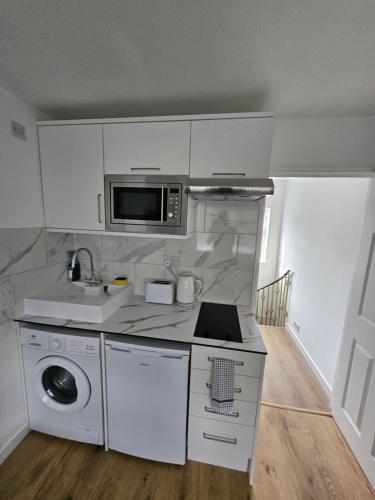 a kitchen with a stove and a microwave at Nice and Cosy One Bed Flat in Carshalton