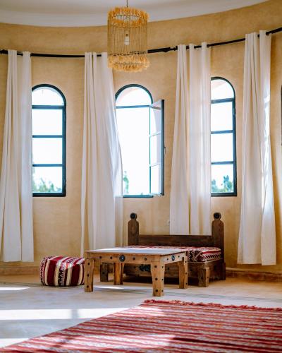 a living room with a table and windows at RIAD YANITRI Piscine chauffée in Essaouira