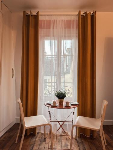 une table et deux chaises devant une fenêtre dans l'établissement Studio indépendant près de Montmartre, à Paris