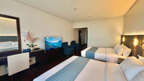 a hotel room with two beds and a flat screen tv at Mountain view room at Forest Lodge Hotel, Camp John Hay-Private unit 549 in Baguio