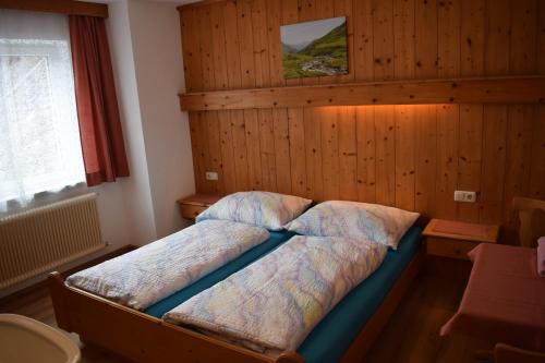 een bed in een slaapkamer met een houten muur bij Apart Gertrud in Kappl