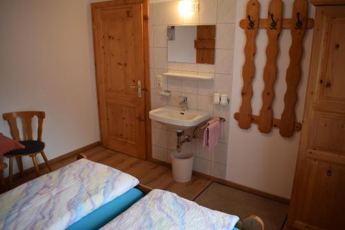 een kleine badkamer met een wastafel en een bed bij Apart Gertrud in Kappl