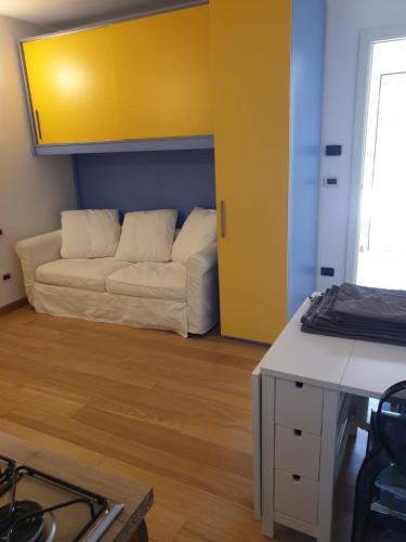 a living room with a white couch and a yellow wall at Residence natura beach in Lido di Volano