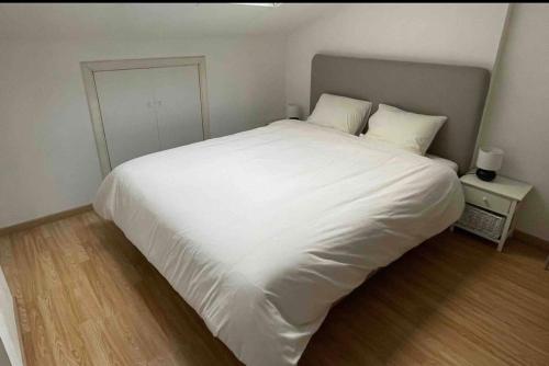 un grande letto bianco in una camera da letto con pavimento in legno di Cosy house a Waterloo
