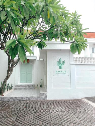 a white building with a green door and a tree at Kaktus Boutique Apartments Bali - ADULTS RETREAT in Legian