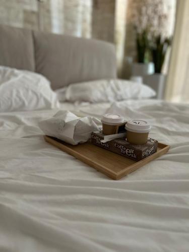 2 tazas en una bandeja de madera en una cama en Pietra Antica Luxury, en Sannicandro di Bari