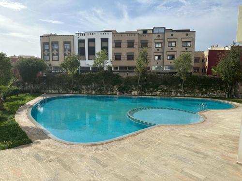 una gran piscina azul con edificios en el fondo en Résidence Les Jardins Du Mazagan, en El Jadida
