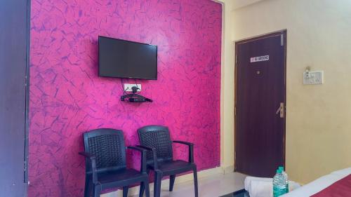 a room with two chairs and a red wall at Hotel Leela Inn Candolim in Marmagao