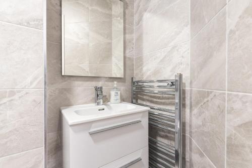 Baño blanco con lavabo y espejo en Ferncourt, en Leopardstown