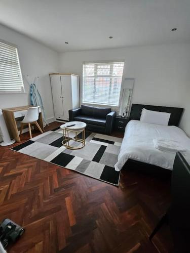 a bedroom with a bed and a couch and a table at Nice and Cosy Studio Flat in Carshalton