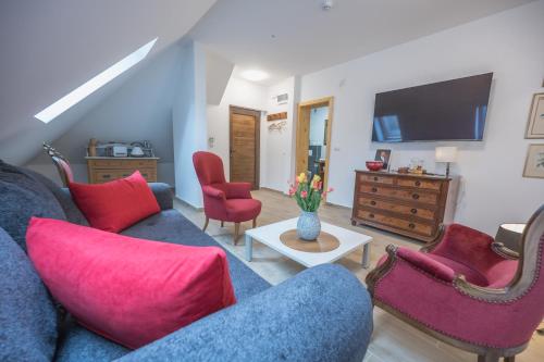 uma sala de estar com um sofá azul e cadeiras vermelhas em Konak Lecic em TrÅ¡iÄ‡