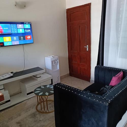 a living room with a black chair and a television at Avril's studio apartment in Mombasa