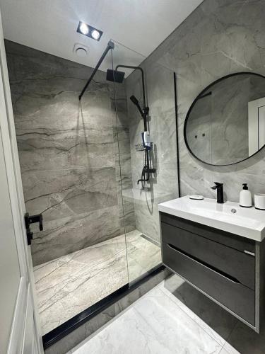 een badkamer met een douche, een wastafel en een spiegel bij Apartment 5 in Doesjanbe