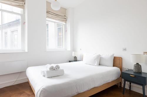 a white bedroom with a large bed with two towels on it at Luxury 1 Bed Apartment Covent Garden Holborn in London