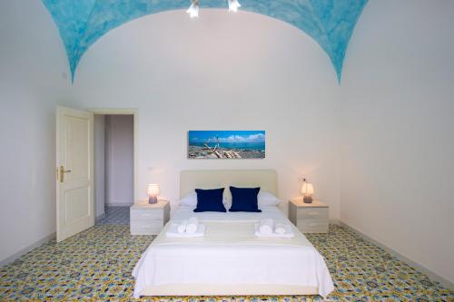 ein Schlafzimmer mit einem weißen Bett mit blauen Kissen in der Unterkunft AMORE RENTALS - Casa Barbera A in Positano