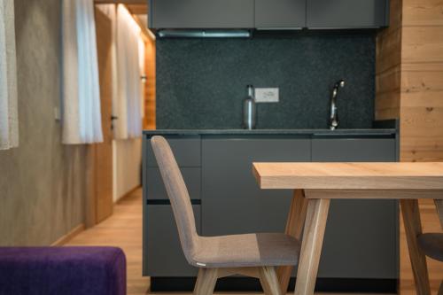 a kitchen with a wooden table and a sink at Vivi Suites & Spa - Boutique Guest House Molveno in Molveno