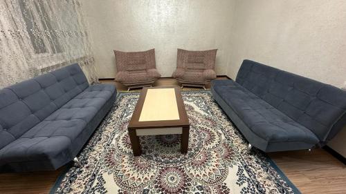 ein Wohnzimmer mit 2 blauen Sofas und einem Couchtisch in der Unterkunft Кунжут in Aqtöbe