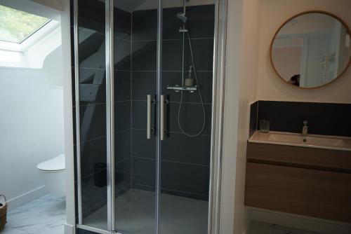 a bathroom with a shower with a sink and a mirror at Les Jardins de Bathilde - Au sein du Château de Bothané in Guidel