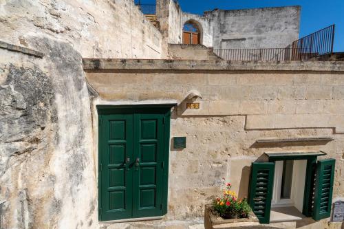 a stone building with a green door and two windows at Terrazze San Martino in Matera