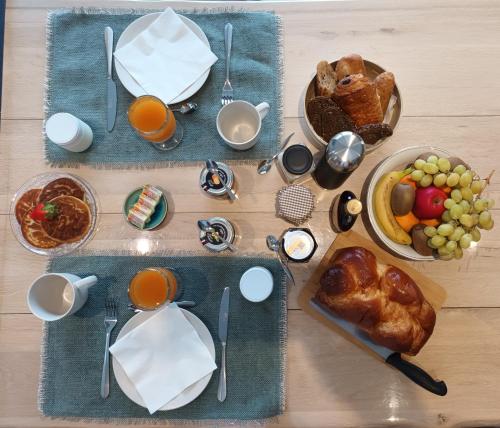 een tafel met een ontbijt van eten en sinaasappelsap bij Aix'capade by Aixkeys avec piscine 5 min plages Fouras in Saint-Laurent-de-la-Prée