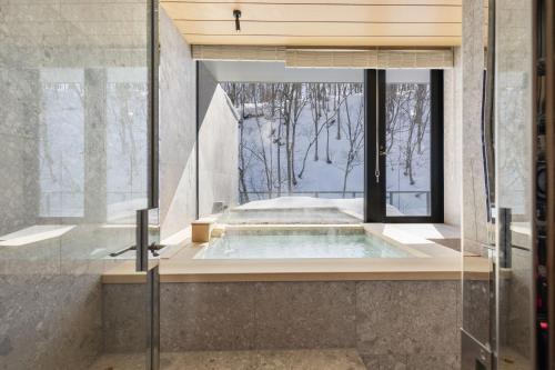 a jacuzzi tub in a bathroom with a window at YAMAKEI Residences in Niseko