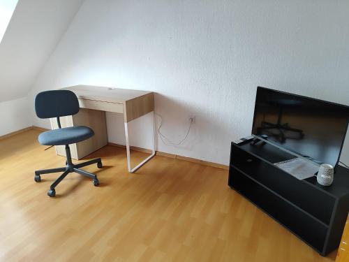 a desk and a chair and a tv in a room at Ferienwohnung Belvie 3 in Butzbach
