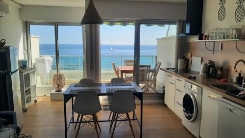 cocina con mesa y sillas y vistas al océano en Happy 7, en Canet-en-Roussillon