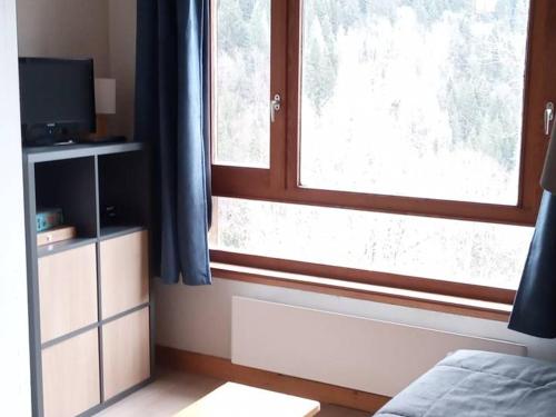 1 dormitorio con 1 cama y una ventana con cortinas azules en Appartement Saint-Jean-d'Aulps, 1 pièce, 6 personnes - FR-1-573-71, en Saint-Jean-dʼAulps
