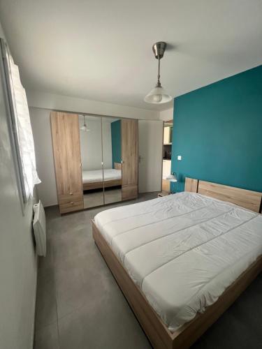 um quarto com uma cama grande e uma parede azul em T2 tout confort avec jardin em Balaruc-les-Bains