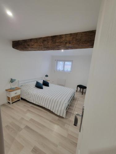 a white bedroom with a bed and a wooden floor at le logis de la forêt in Parçay-les-Pins