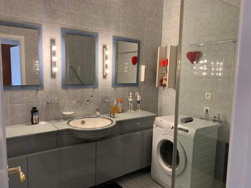 a bathroom with a sink and a washing machine at Apartment Linkerover- City Centre & Cathedral view in Antwerp