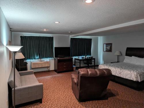 Habitación de hotel con cama, sofá y silla en Gettysburg Inn and Suites en Gettysburg