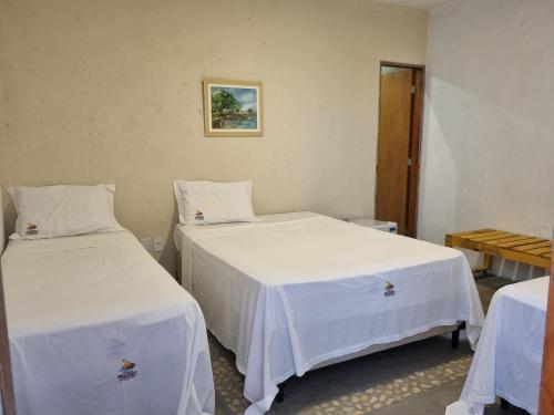 two beds in a room with white sheets at Pousada Prazeres do Velho Chico 