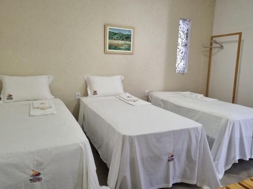 two beds in a room with white sheets at Pousada Prazeres do Velho Chico 