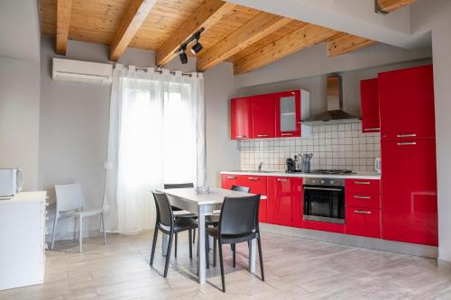 a kitchen with red cabinets and a table and chairs at "Il Segreto" Vista Panoramica sulle Isole Eolie con Piscina, palestra e WiFi in Patti