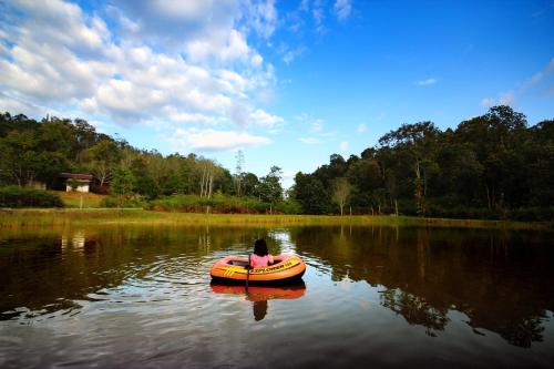 a person in an orange boat on a lake at Labang Guesthouse Bario in Bario